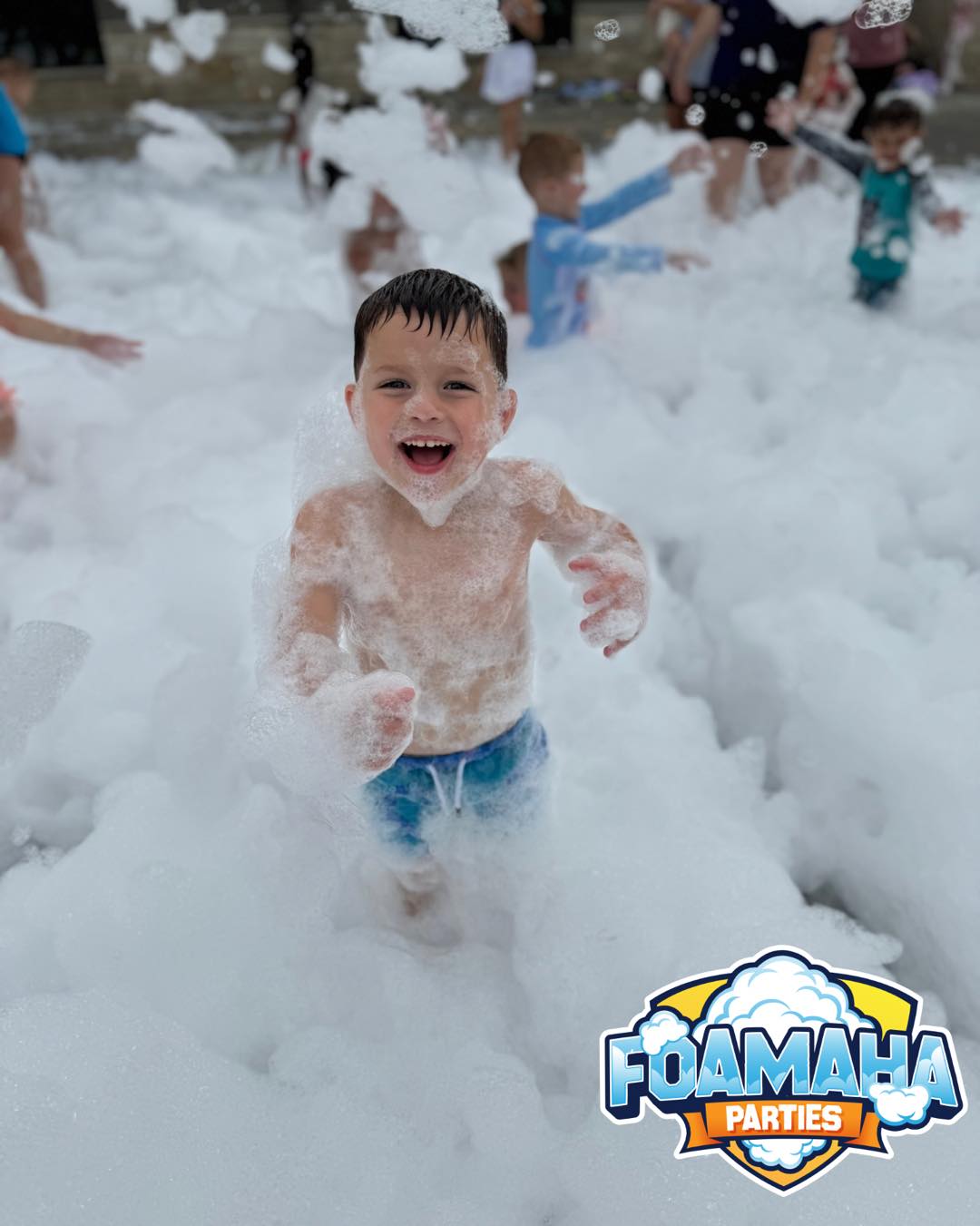 Boy running through a sea of foam at a Foamaha party, smiling ear to ear