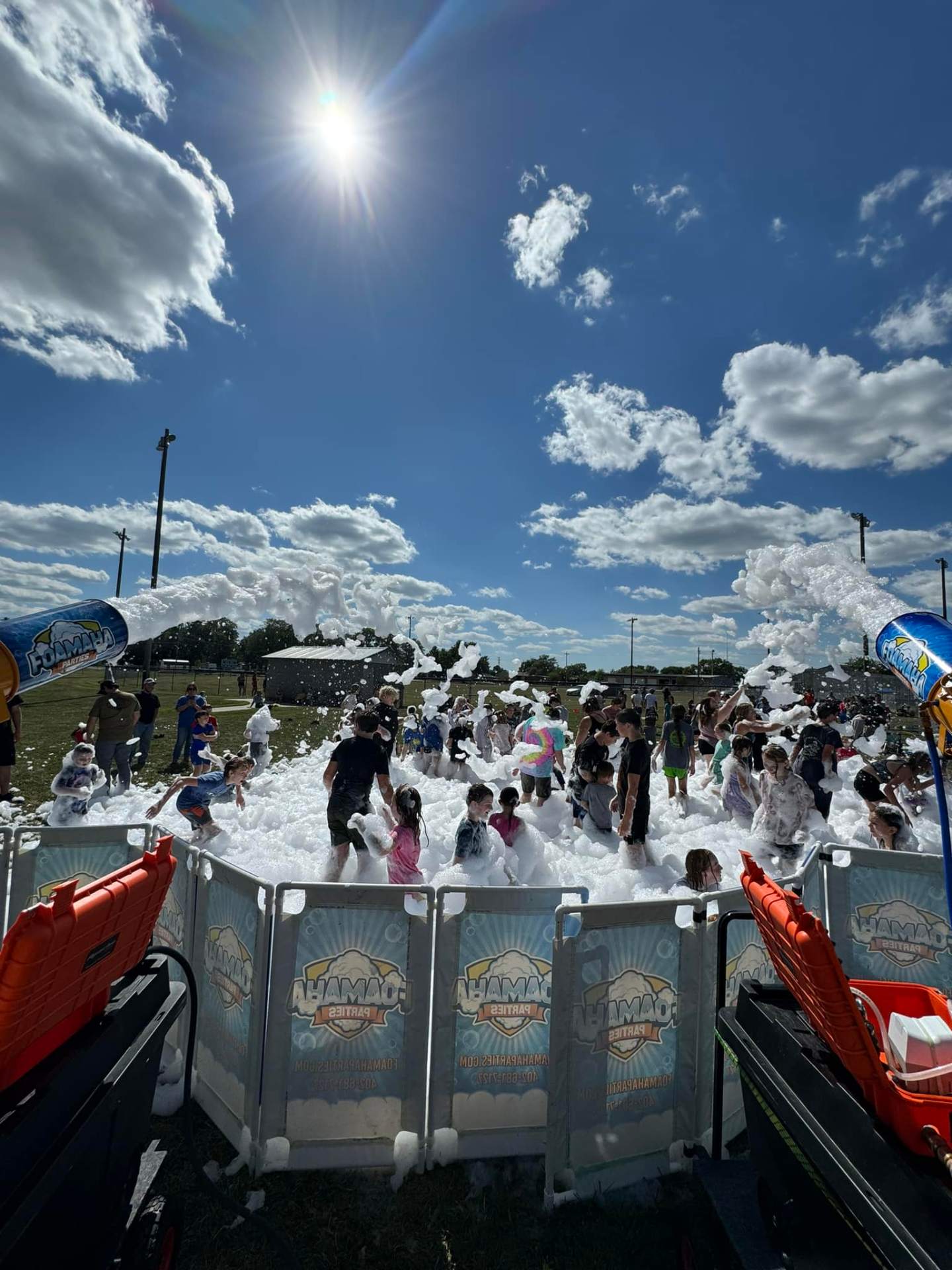 Wide foam pit packed with kids under a bright blue Nebraska sky
